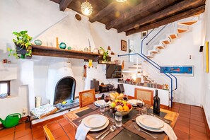 A dining area with a fireplace, a table set for two, and a staircase leading to an upper level. - Antica Torre With Garden in Carona (Lugano)