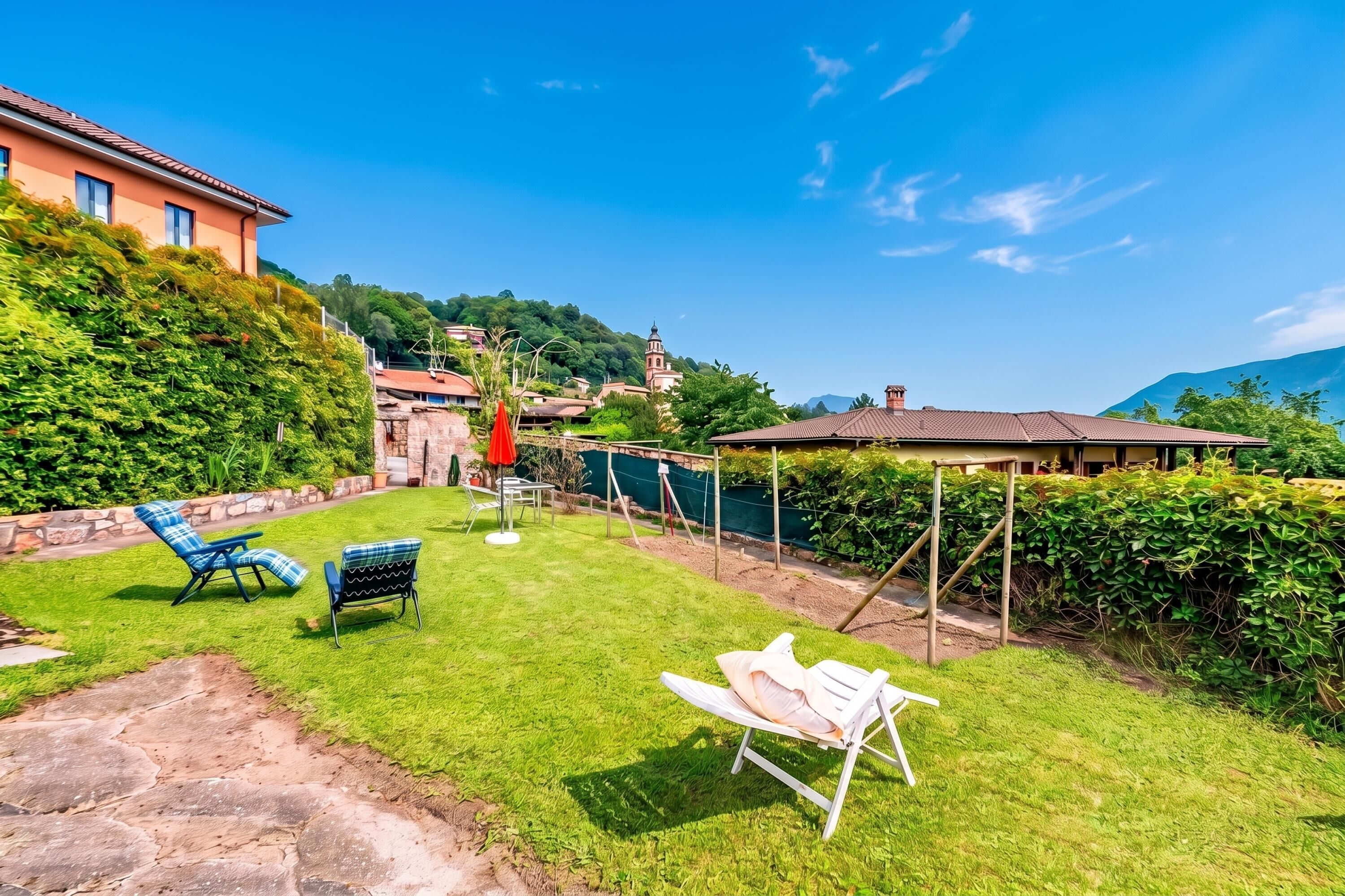 A well-maintained garden with a lawn, outdoor furniture, and a building with a red roof.