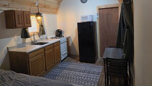 Une cuisine de taille réduite, dotée de meubles de rangement en bois, d’une cuisinière, d’un four à micro-ondes et d’un réfrigérateur.