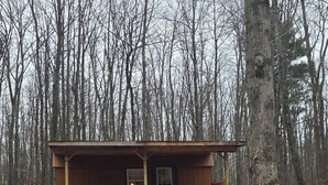 Une cabane en bois avec une véranda, une cheminée et une fenêtre.