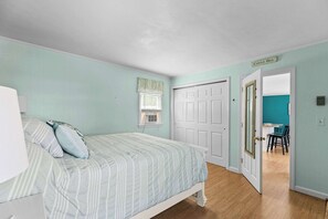 Une chambre à coucher avec un lit, une fenêtre agrémentée d’une lambrequin, une porte et une pancarte sur laquelle on peut lire « Castle Hill ».