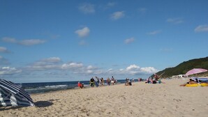 En strand med folk, der går, sidder og solbader.