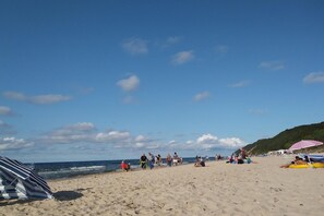 Una spiaggia con persone che camminano, siedono e prendono il sole.