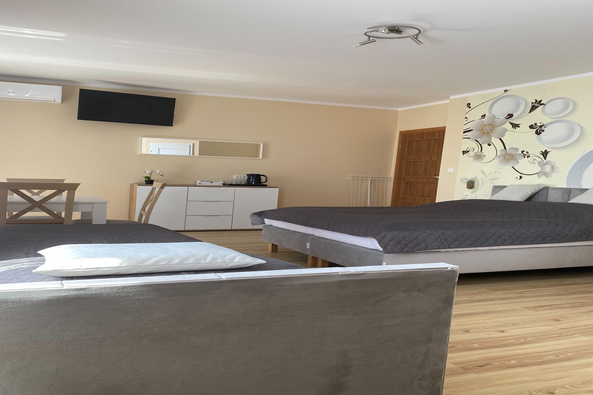 Ein Hotelzimmer mit zwei Betten, einem Schreibtisch, einem Stuhl, einem Fernseher und einer Wanddekoration.