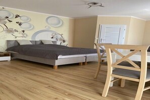 Quarto com cama, piso de madeira e uma escrivaninha com cadeira.