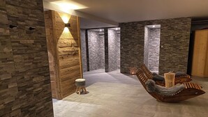 Un interior moderno con paredes de piedra, un banco de madera con cojines y un taburete pequeño.