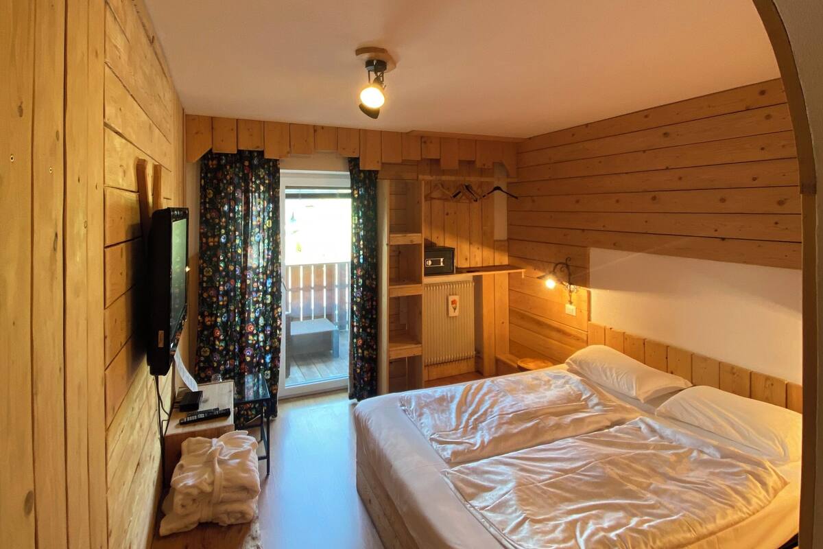 A cozy bedroom with a wooden bunk bed, a television, and a small seating area with a table and chairs.
