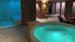Zona de spa con hidromasaje, asientos de madera y paredes de piedra.