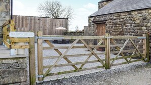 Una valla de madera que da paso a un edificio de piedra con la leyenda "Holiday Cottage".