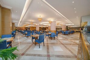 Un amplio hall de hotel con varias zonas de estar, una columna decorativa central y un diseño de techo moderno.