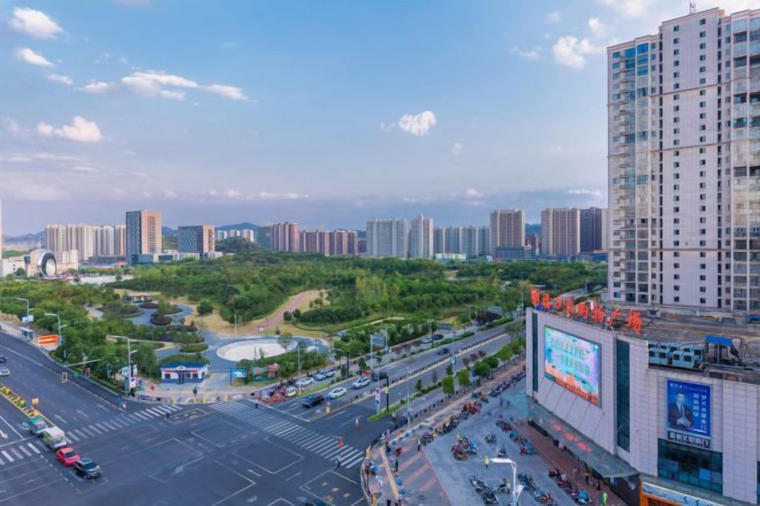 A cityscape with high-rise buildings, a road with vehicles, and a billboard.