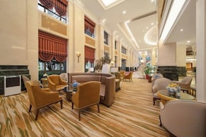 A hotel lobby with a high ceiling, a marble reception desk, and a seating area with sofas and armchairs. - Jinzhai Hongfu Garden Yuehai Hotel (Dabie Mountain Yuboyuan) (Jinzhai)