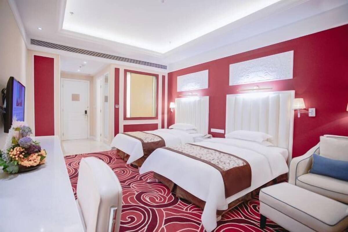 A hotel room with two beds, a desk, and a chair.