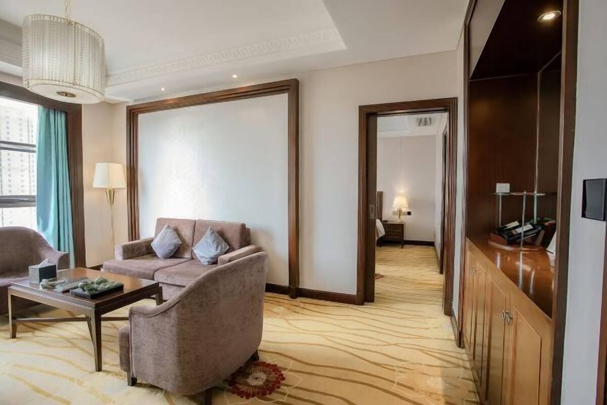 A hotel room with a sofa, armchair, coffee table, and a large mirror.