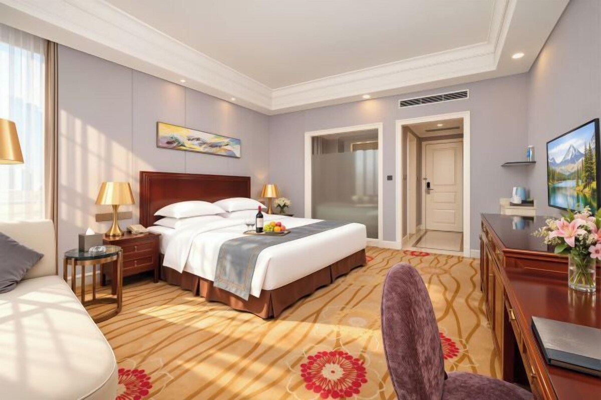 A hotel room with a large bed, bedside tables, a desk, and a chair.