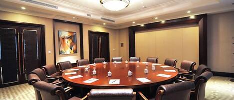 A conference room with a round table, chairs, and a projector screen.