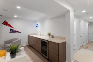 A modern bathroom with a sink, mirror, and towel rack. There are two potted plants on the counter.