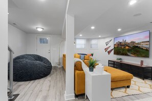 A modern living room with a large flat-screen TV, a bean bag, and a sofa. - Modern 4 Bed, 3.5 Bath Home | Near Sox & McCormick (Chicago)
