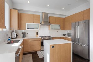 A modern kitchen with wooden cabinets, stainless steel appliances, and a white countertop.