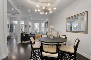 A modern dining area with a round table, black and white checkered rug, and a chandelier. - Modern 4 Bed, 3.5 Bath Home | Near Sox & McCormick (Chicago)