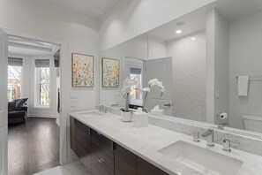 A modern bathroom with a large mirror, two sinks, and a dark wooden cabinet. - Modern 4 Bed, 3.5 Bath Home | Near Sox & McCormick (Chicago)