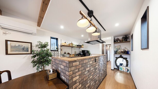 Une cuisine moderne dotée d’un îlot central, de poutres en bois au plafond et de luminaires suspendus.