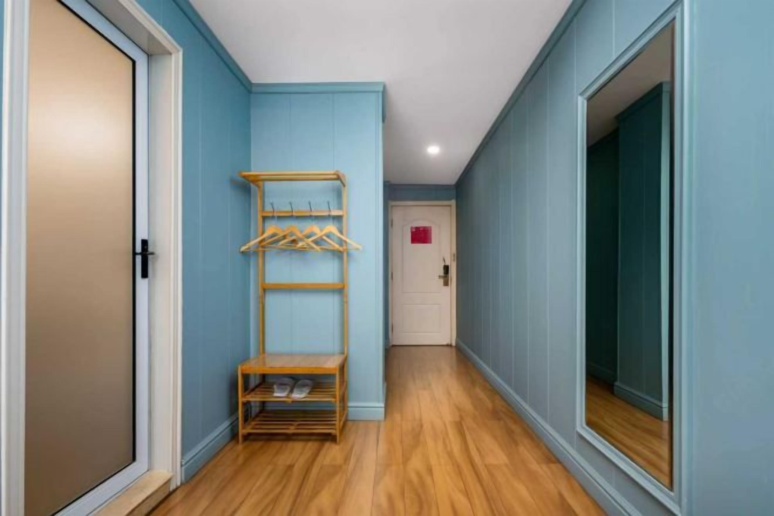 Un corridoio con un portasalva-scarpe in legno, una porta e una finestra.