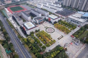 Vista aérea de un campus con edificios, un campo deportivo y una plaza central con árboles.