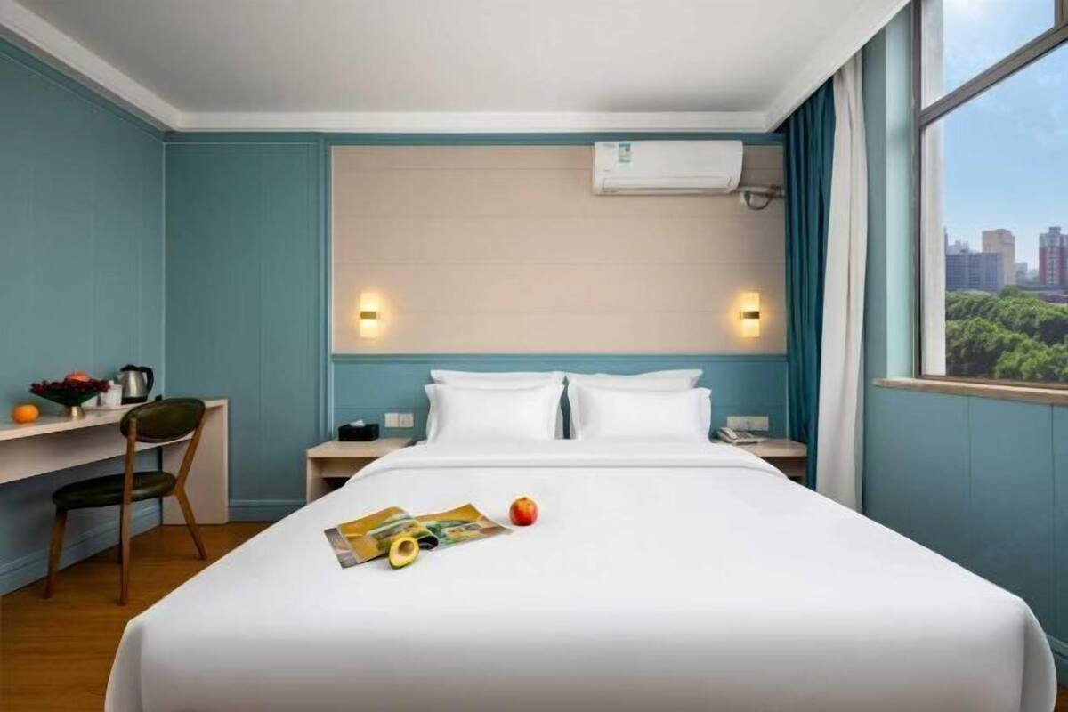Una habitación de hotel con una cama, un escritorio y una ventana con vistas a la ciudad.
