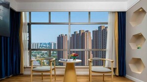 A room with a large window, two chairs, a small round table, and a decorative wall.