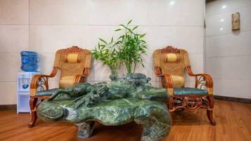 A room with a marble coffee table, two wicker chairs, and a bamboo plant.