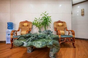 Una habitación con una mesa de centro de mármol, dos sillas de mimbre y una planta de bambú.