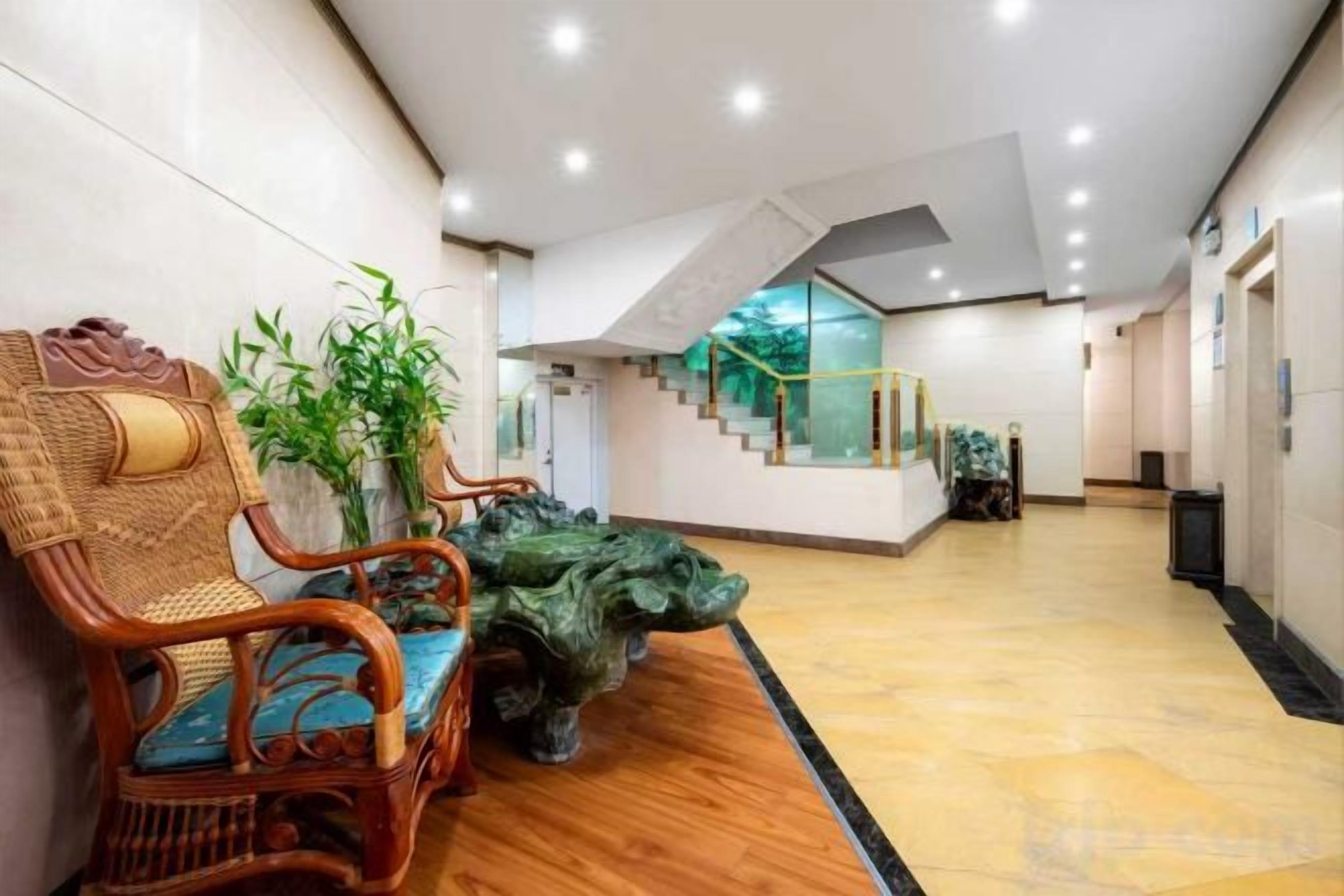 Een hal met een trap, een zithoek met stoelen en een decoratieve plant.