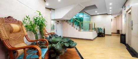 A lobby with a staircase, seating area with chairs, and a decorative plant.