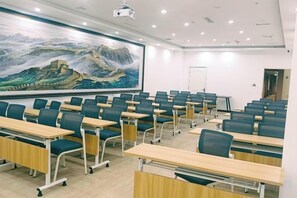 A classroom with rows of desks and chairs, a projector screen, and a large painting on the wall. - Qitian Boutique Hotel (Shangqiu)