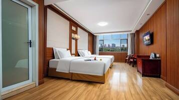 Quarto de hotel com cama, escrivaninha, cadeira e vista da cidade.