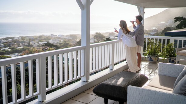 A balcony with a white railing overlooking a coastal view.