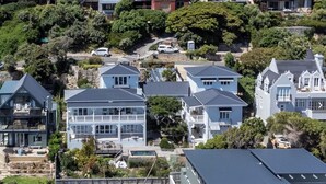 A residential area with multiple houses, including a two-story house with a balcony and a large house with a swimming pool.
