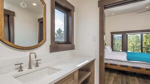 Un baño moderno con un espejo grande, un lavabo y una ventana.