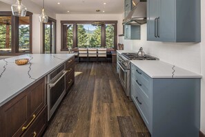 A modern kitchen with a large island, built-in appliances, and a dining area with a view.