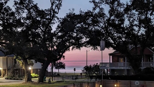 A waterfront property with outdoor seating, a swimming pool, and a view of the ocean at dusk.