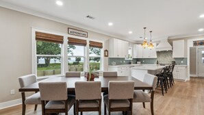 A modern kitchen with white cabinets, a large island, and a dining area with a table and chairs.