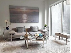 Uma sala de estar moderna com sofá, mesa de centro e uma pintura grande na parede.