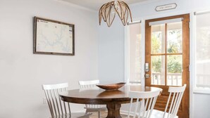 A dining area with a wooden table, white chairs, a map on the wall, and a door with a 'STAY AWAY' sign. - Wake & Lake - Sleeps 8, Big Water Views! + More! (Sparta)