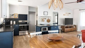 A modern kitchen with a central island, white cabinets, and a dining area with a round table. - Wake & Lake - Sleeps 8, Big Water Views! + More! (Sparta)