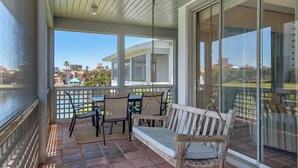 A covered patio with a wooden bench, a table, and chairs. - Lake View Villa at Hidden Dunes! (Miramar Beach)