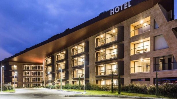 A hotel building with multiple floors, large windows, and a sign indicating it is a hotel.