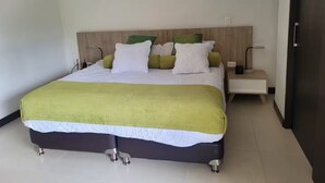 A neatly made bed with a green and white bedspread, a wooden headboard, and a bedside table with a lamp.