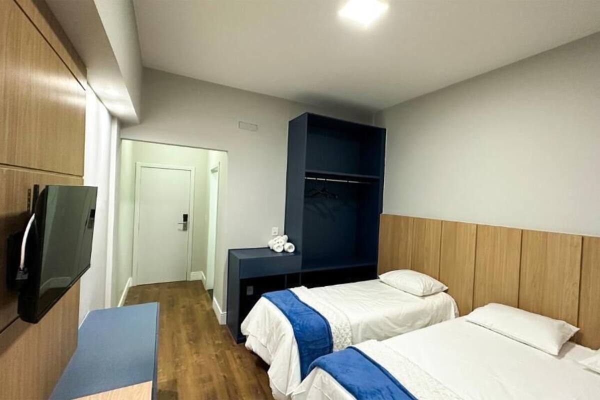 A hotel room with two beds, a TV, a desk, and a wardrobe.