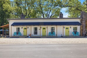 A motel with a covered porch, multiple doors, and outdoor seating.